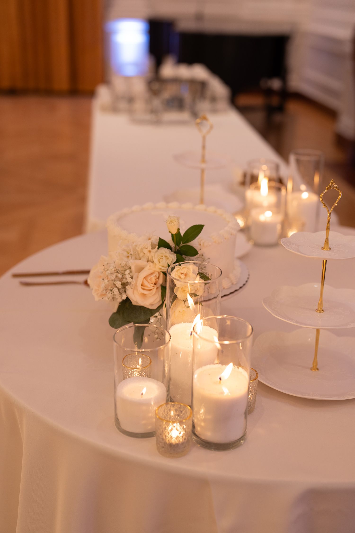 White table settings with glowing candles and greenery create an intimate wedding reception atmosphere.