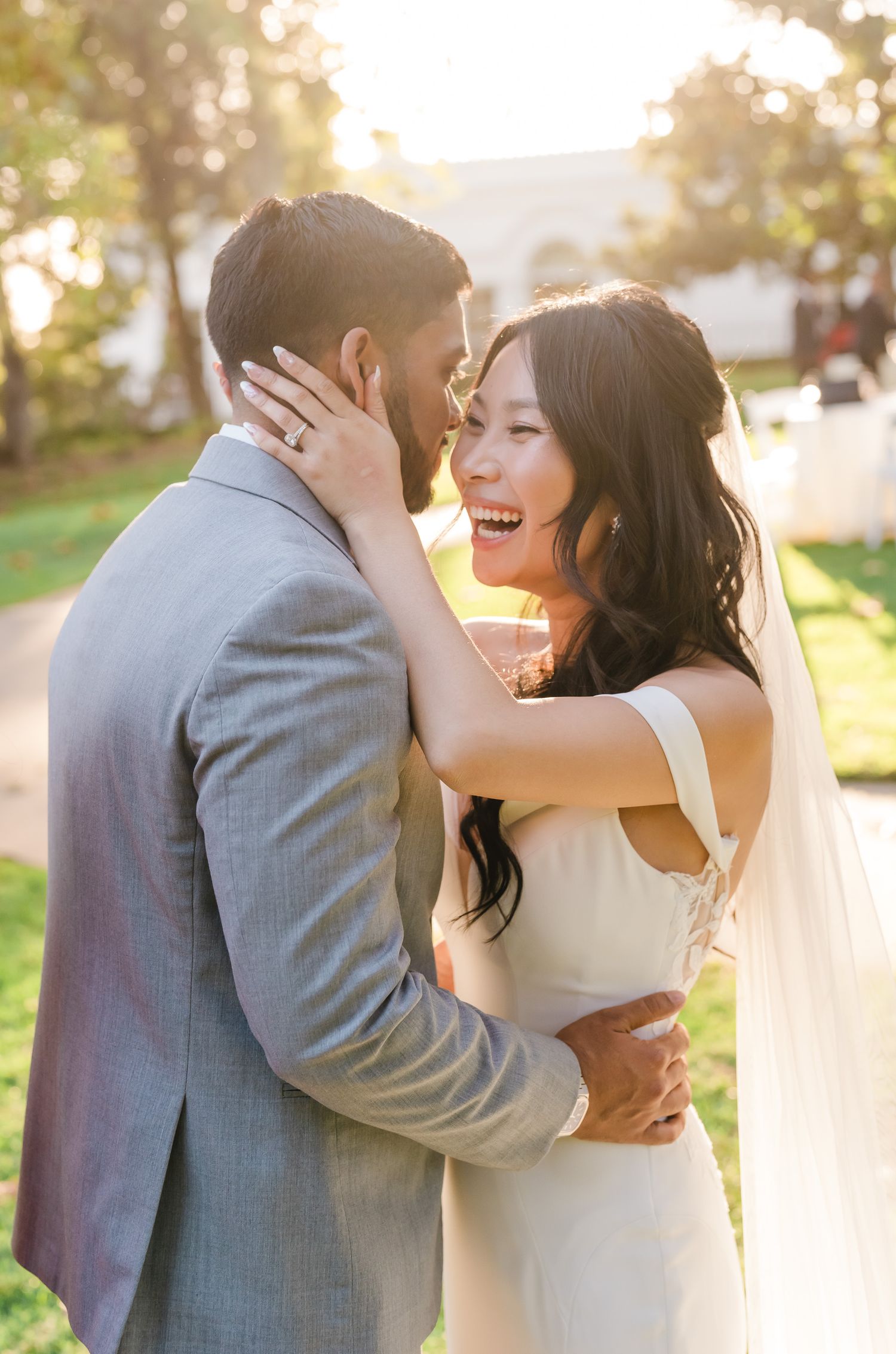 A couple shares an intimate embrace outdoors during a sunset wedding photoshoot with a dreamy golden glow.