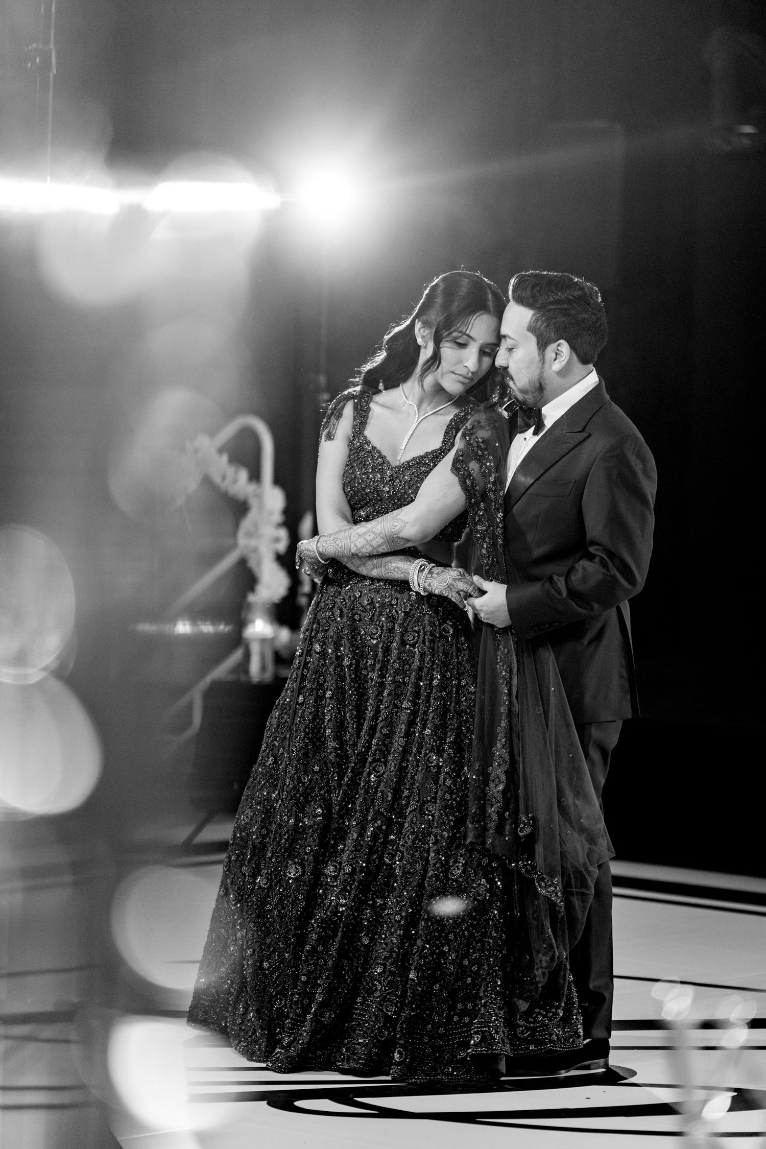 Couple dancing in formal attire with a sparkly black dress on a monochrome dance floor.