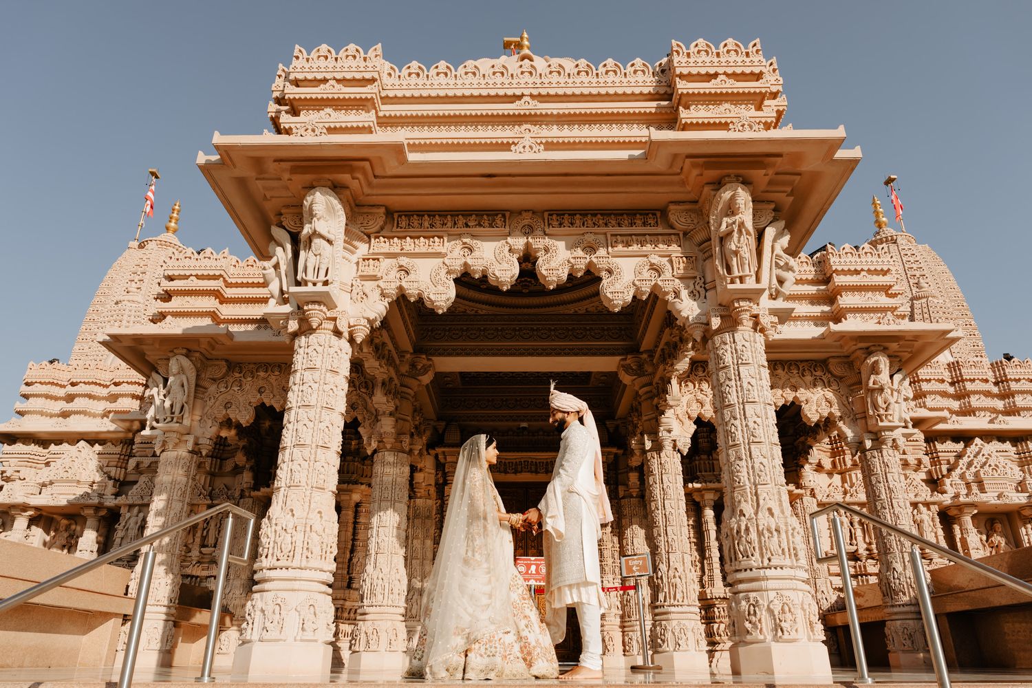 Ancient temple architecture with intricate carvings and domed structures against blue sky.