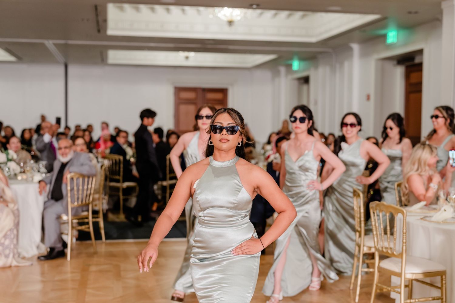 Wedding guests participate in a fun group dance game during the reception in an elegant white ballroom.