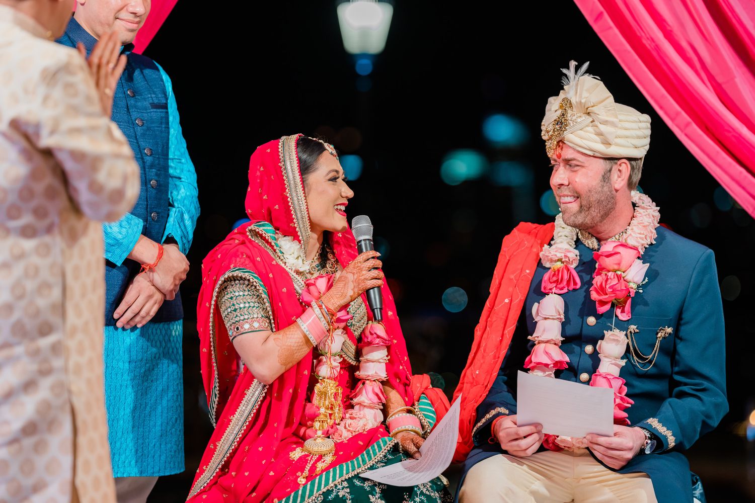 A couple in traditional wedding attire shares a joyful moment during their multicultural wedding ceremony.
