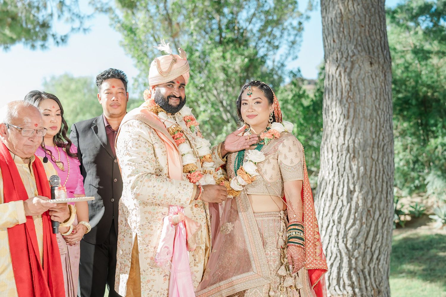Wedding guests celebrate outdoors under tall pine trees during a joyful summer celebration.