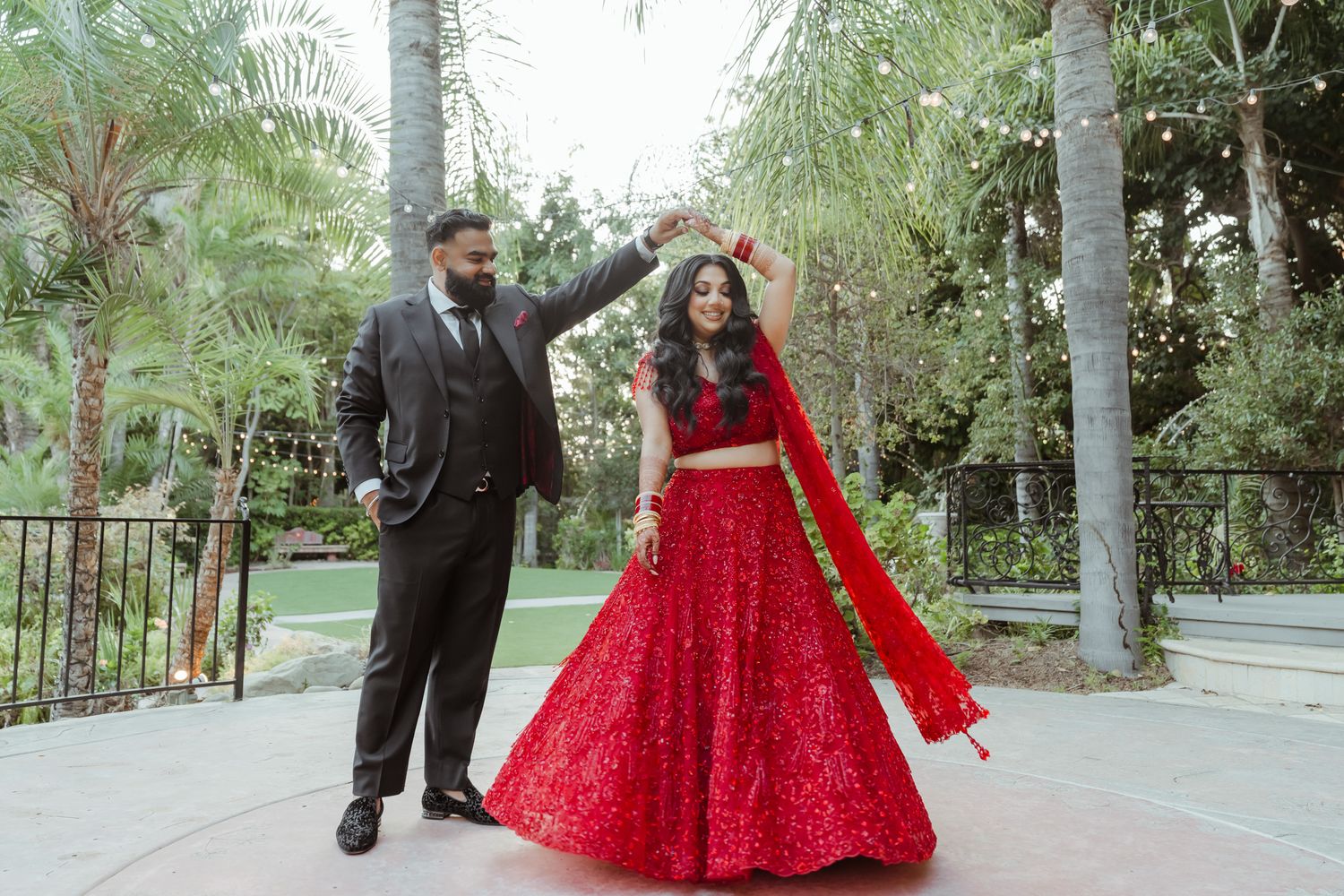 Wedding couple walking and posing along outdoor pathway surrounded by greenery.