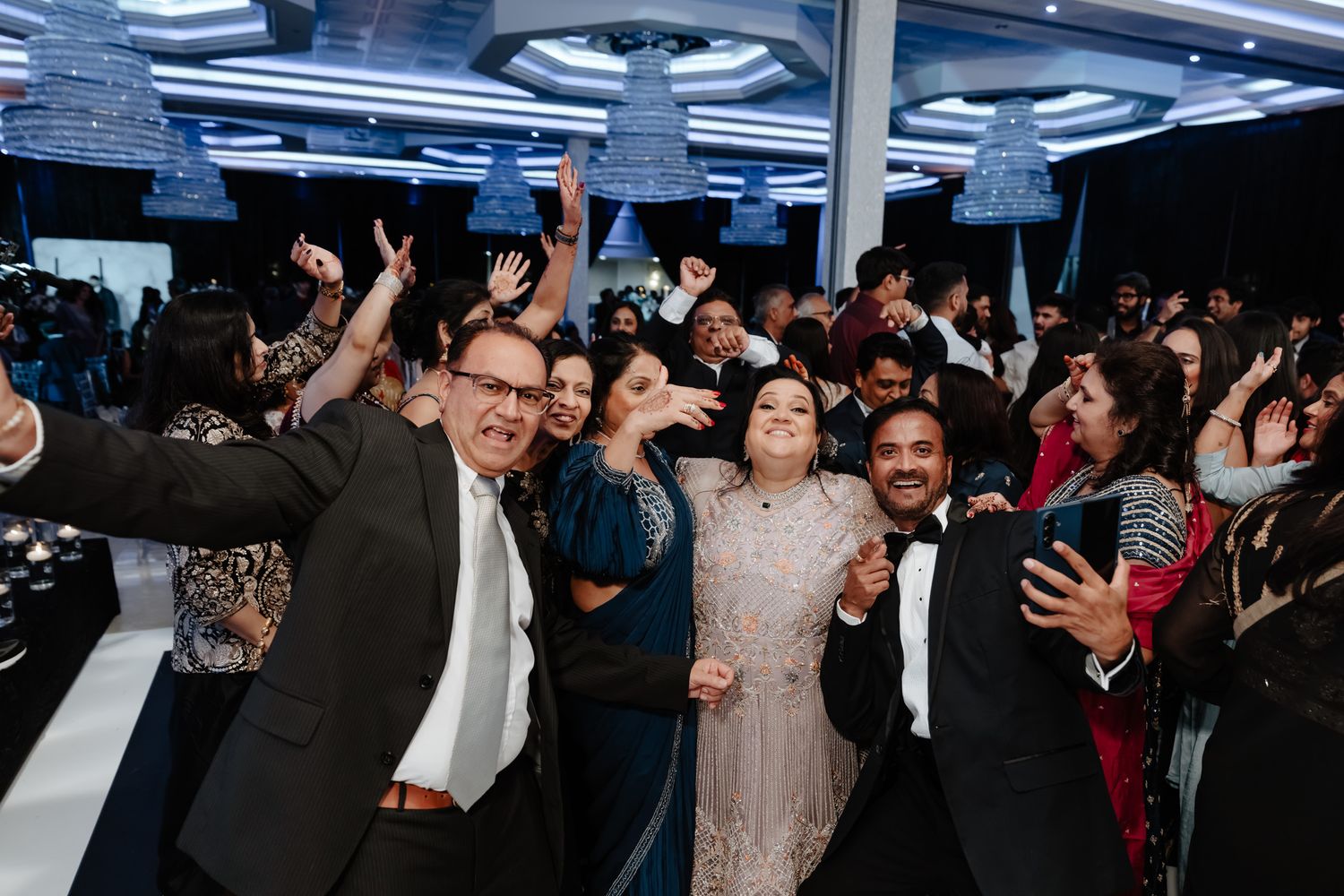 Energetic crowd of wedding guests dancing and celebrating on the dance floor.