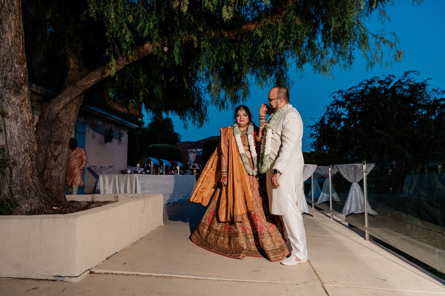 Outdoor wedding ceremony space under large trees with natural lighting and scenic backdrop.