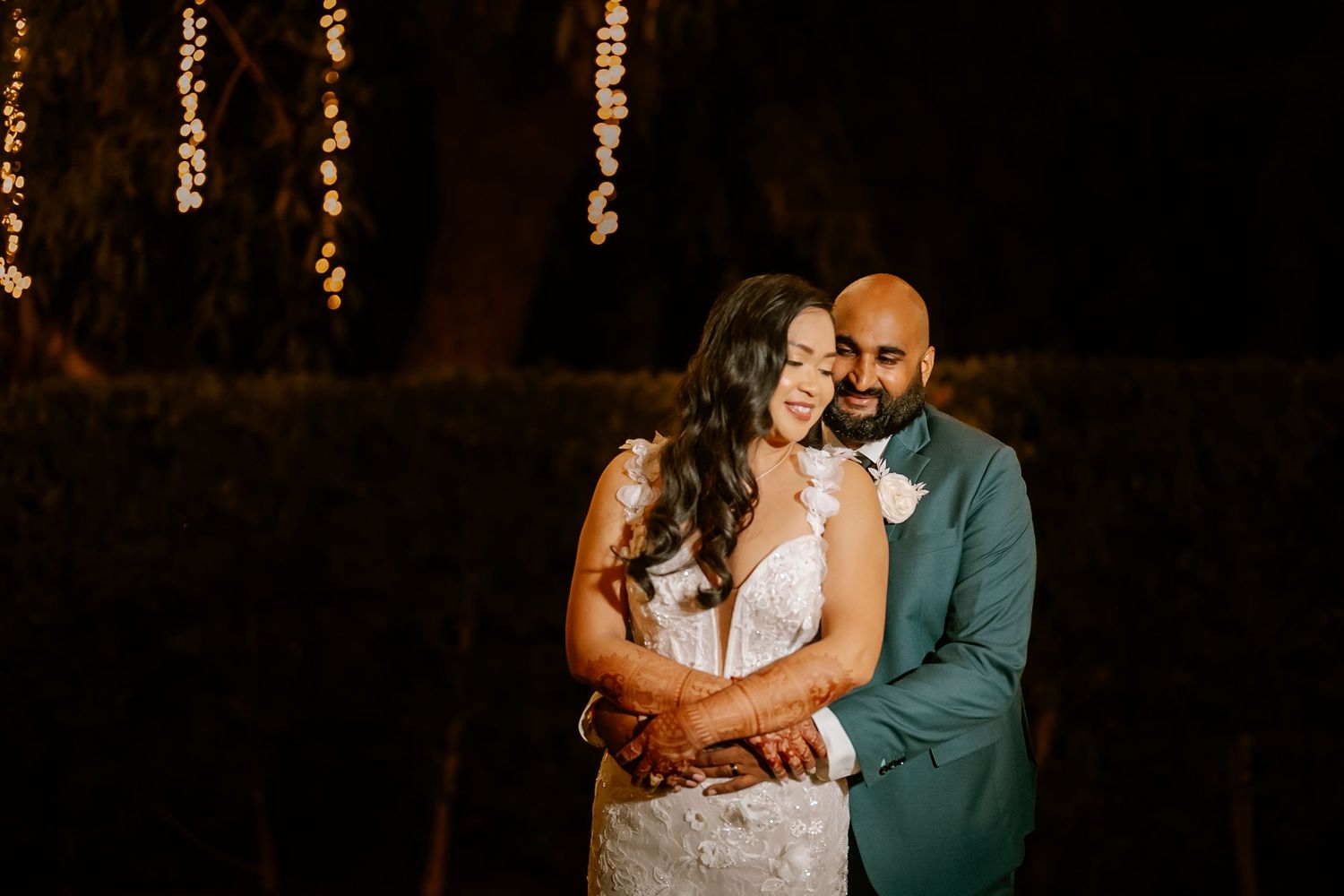 Couple sharing an intimate moment during an evening wedding reception with warm lighting.