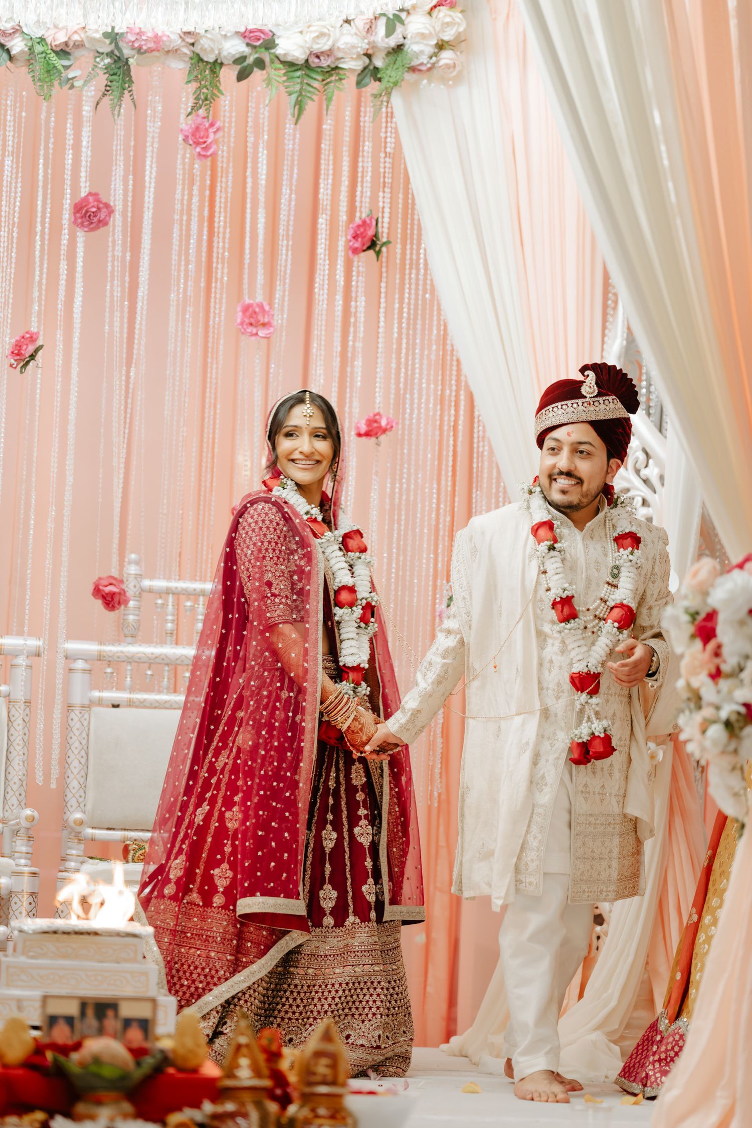 Traditional South Asian wedding decor with pink and white drapes, floral arrangements, and elegant seating.