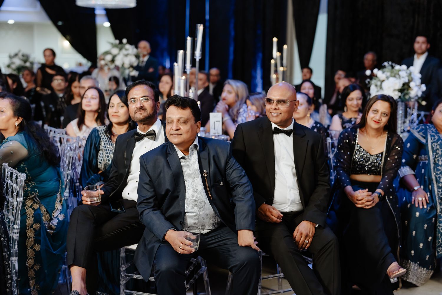 Wedding guests seated in rows watching attentively during an indoor ceremony.