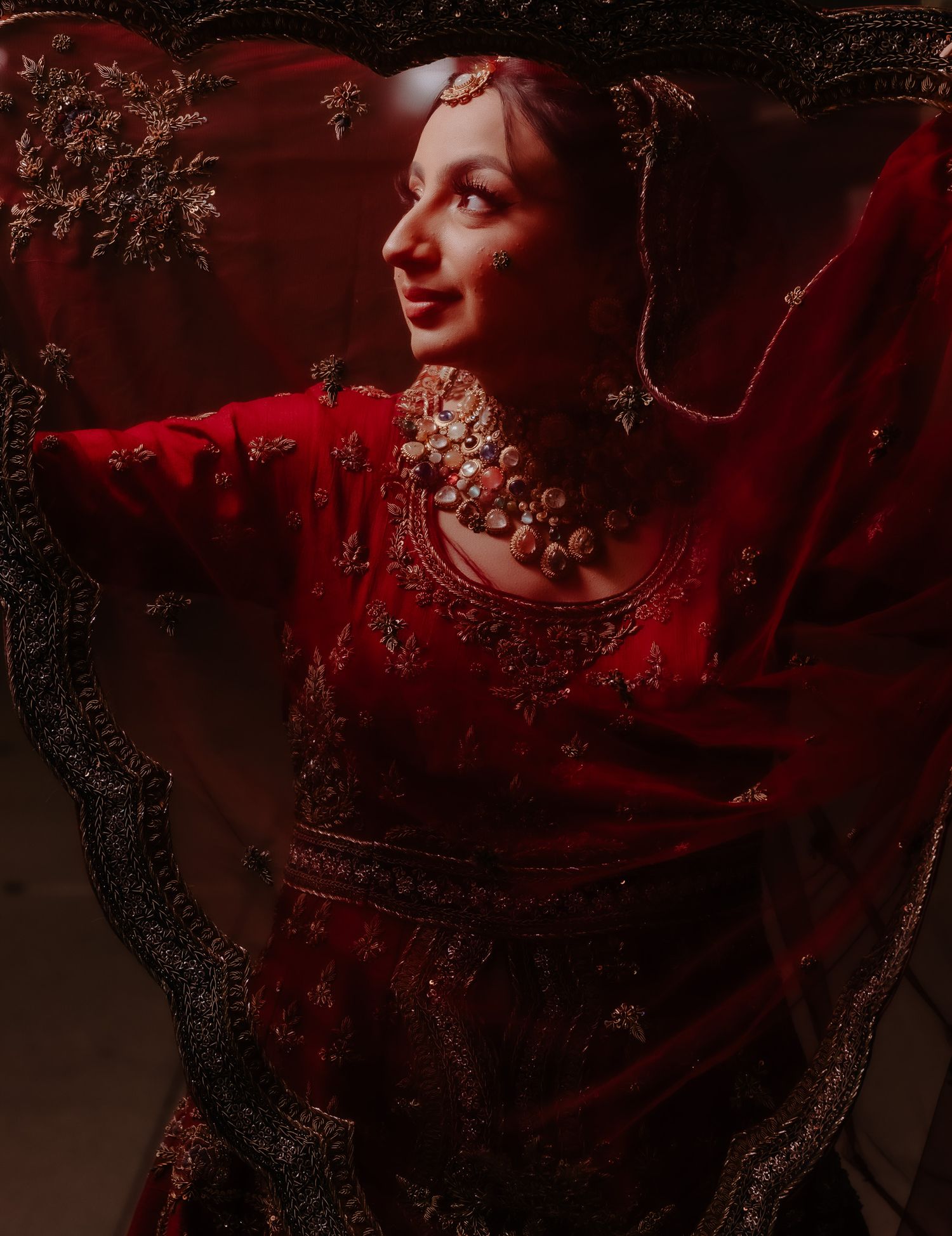Traditional red bridal attire with intricate embroidery details captured in dramatic lighting.