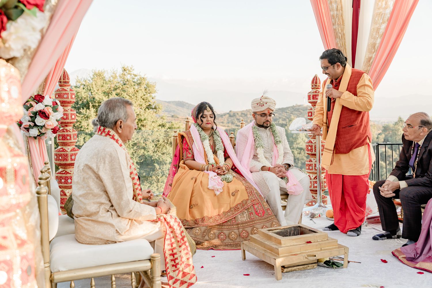 An elegant outdoor wedding ceremony setup with traditional Indian decor and seating arrangements.