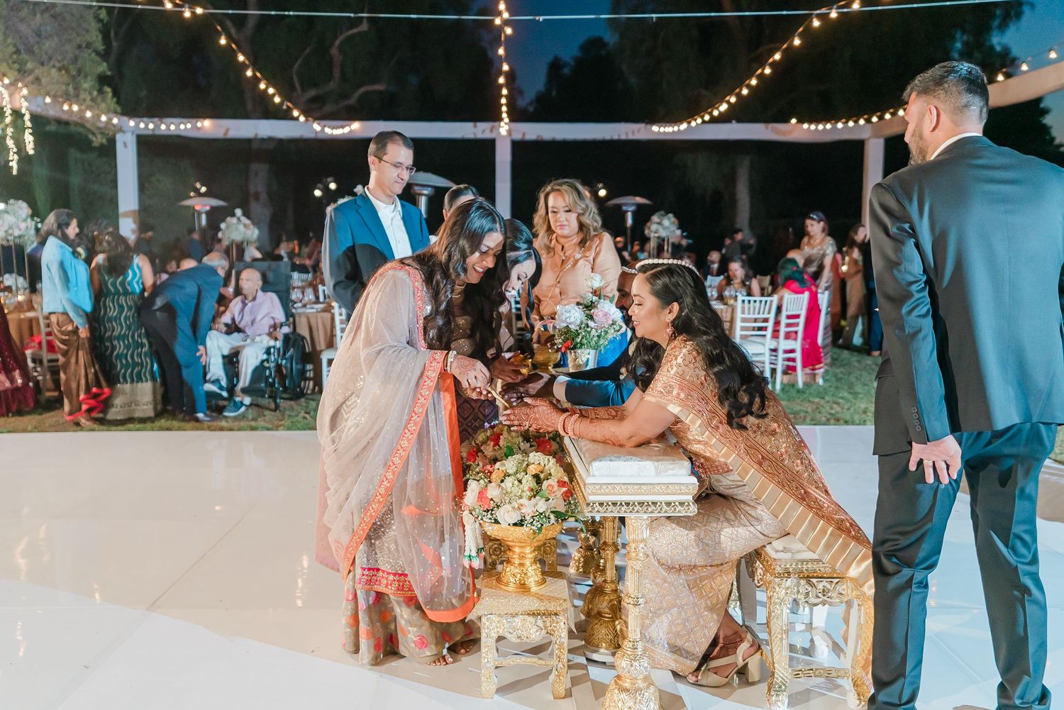 Evening wedding reception with string lights and guests dancing on an outdoor patio.