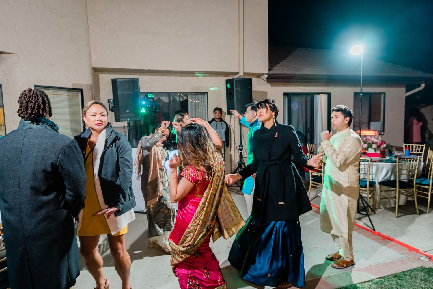 Wedding guests dance and celebrate on the dance floor during a festive reception party under blue lighting.