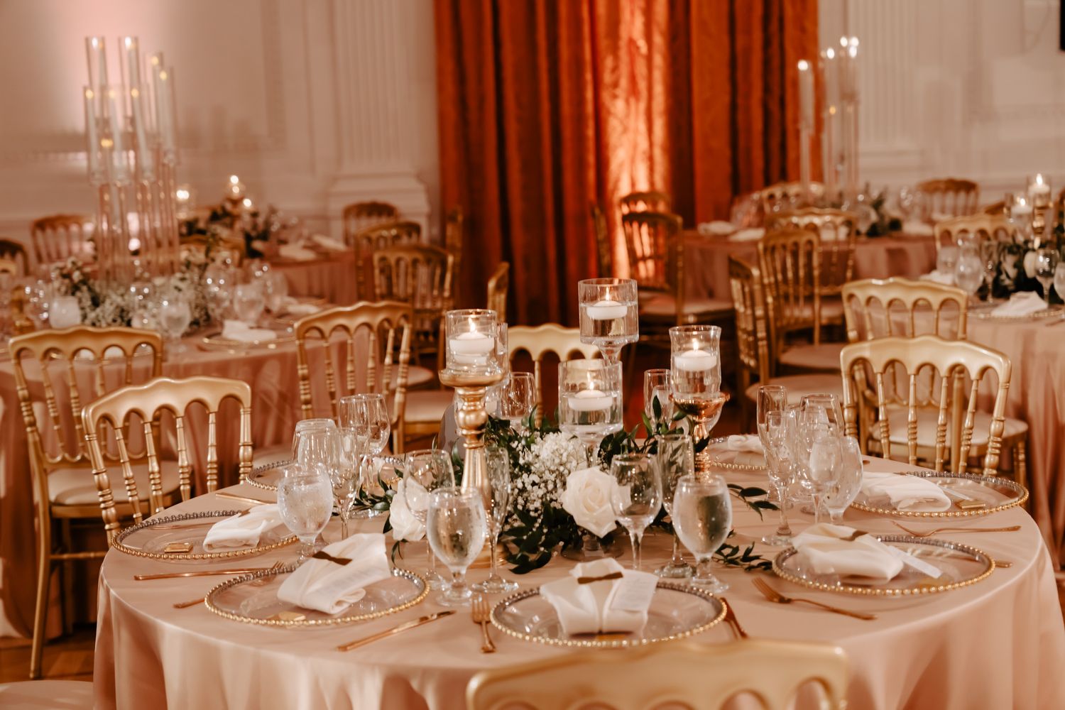 Elegant table settings with crystal glassware and floral centerpieces in warm lighting.