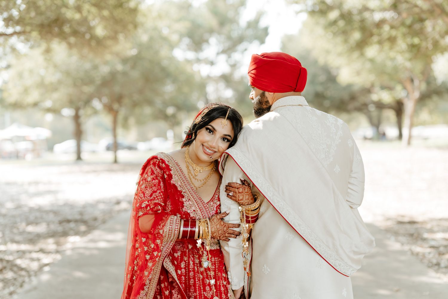 Natural light wedding portraits under trees featuring traditional Indian wedding outfits.