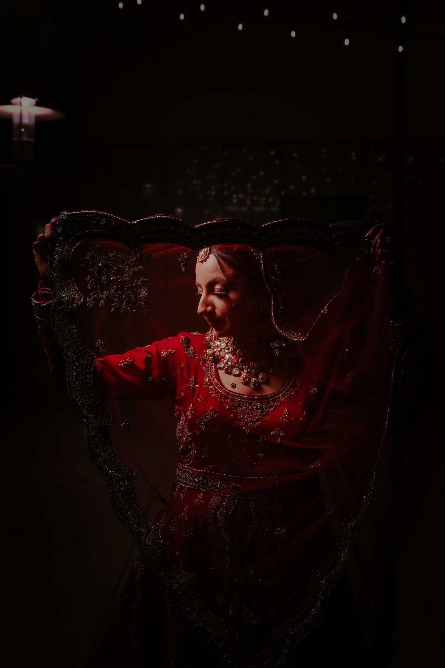 Dramatic red-lit artistic portrait with flowing fabric in dark moody setting.