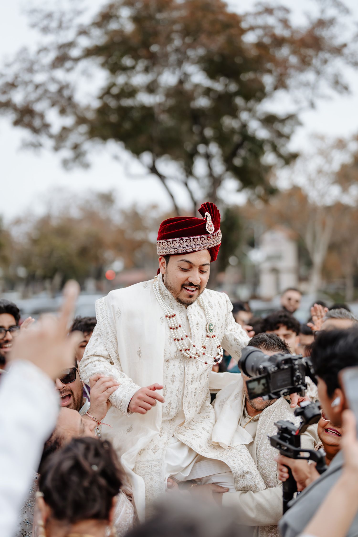 Wedding celebration outdoors with guests in traditional white attire dancing and celebrating.