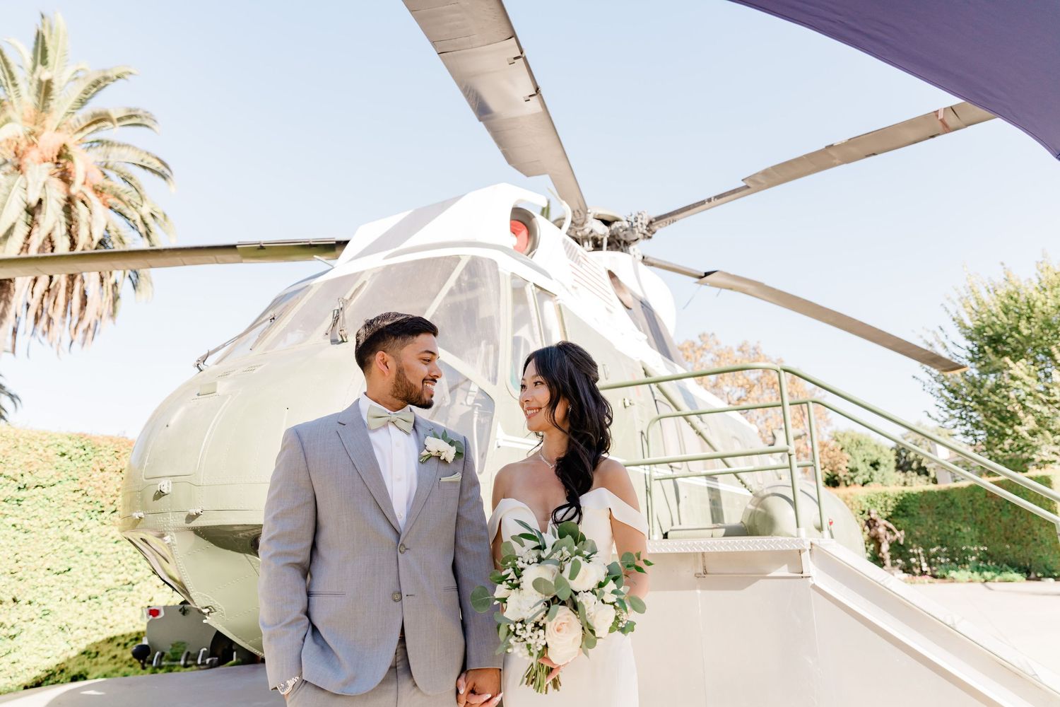Wedding couple embraces near a small aircraft on a sunny day at an airfield.
