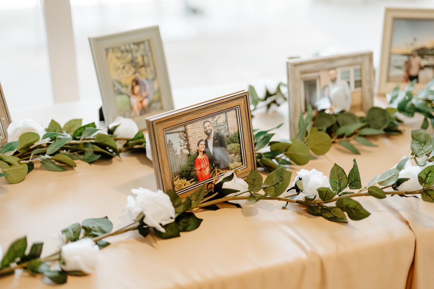 Wedding reception table decorated with eucalyptus garland and vintage photo frames.