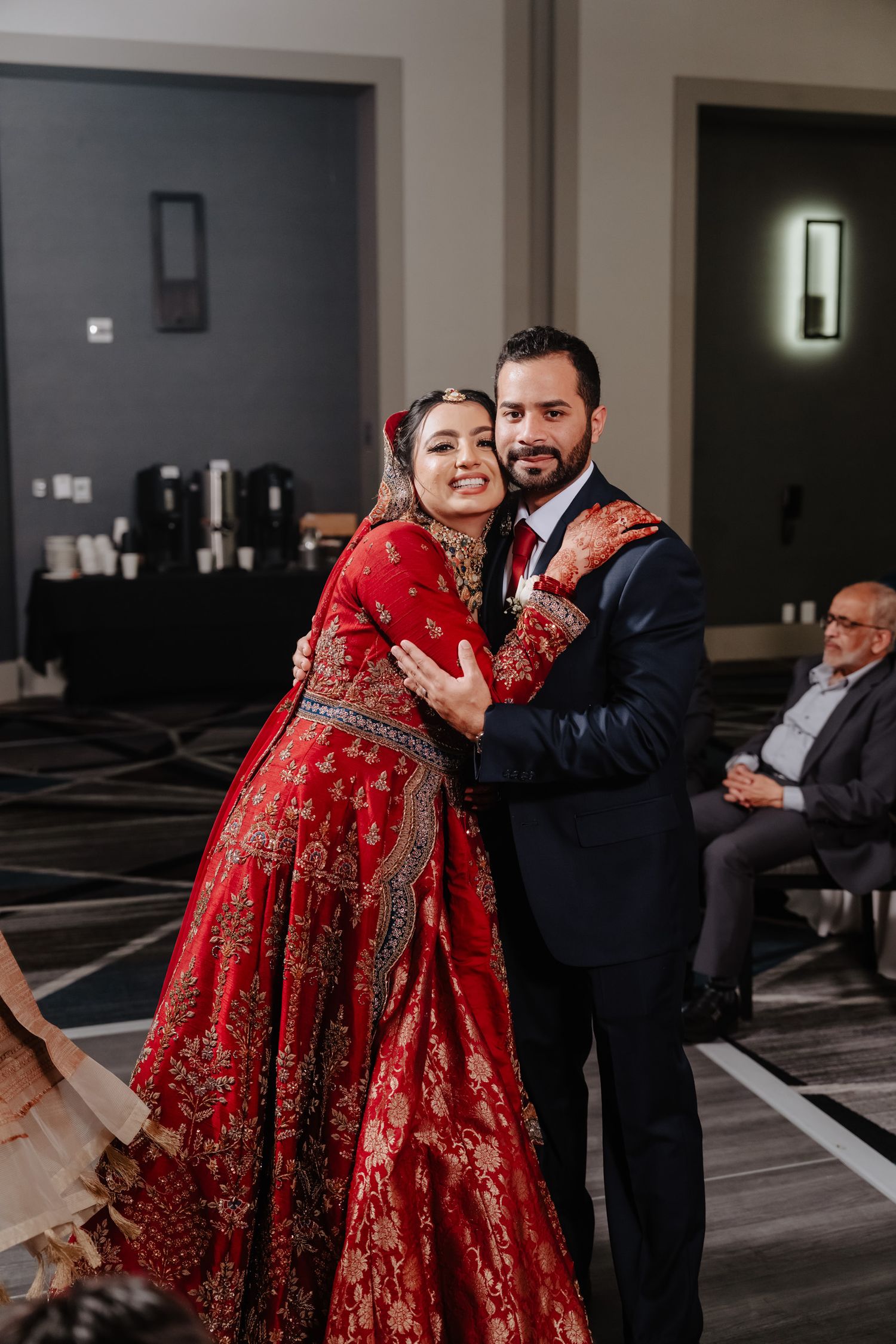 Couple dancing together during an indoor wedding celebration with the bride wearing a stunning red lehenga.