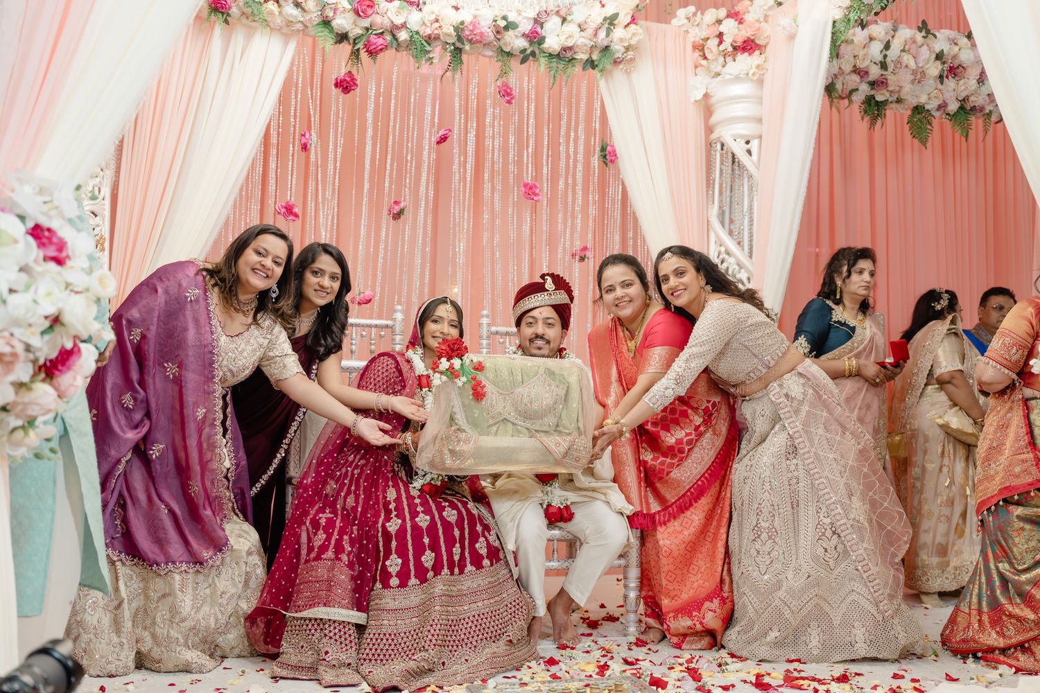 Festive celebration scene with pink drapes and floral decorations at an elegant Indian wedding ceremony.