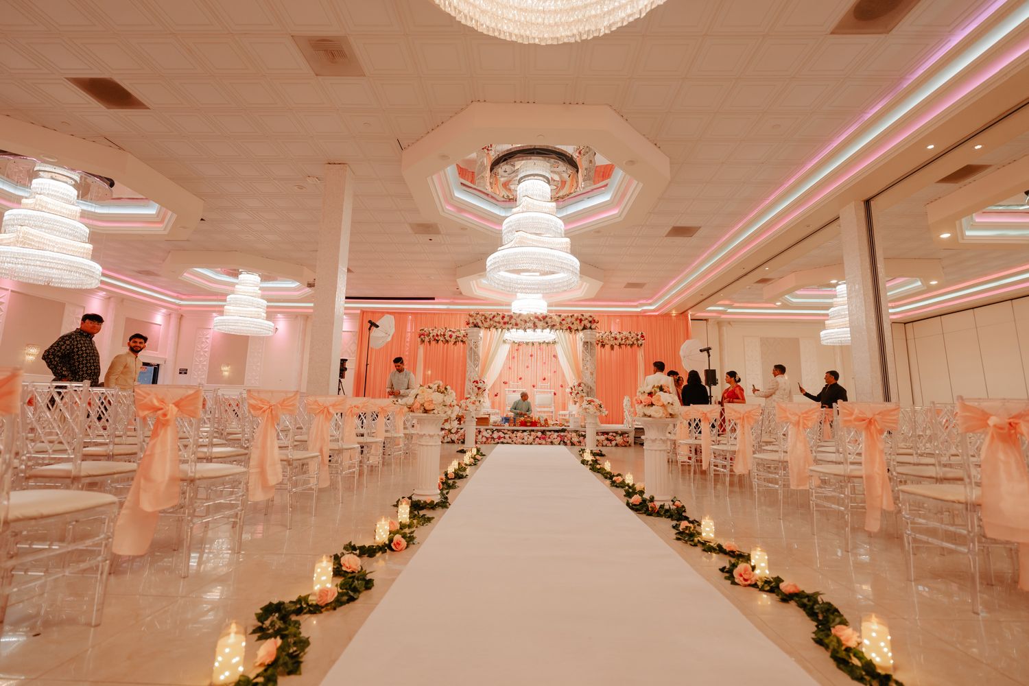 Panoramic view of an elegant wedding venue with pink lighting and white drapes creating a romantic atmosphere.