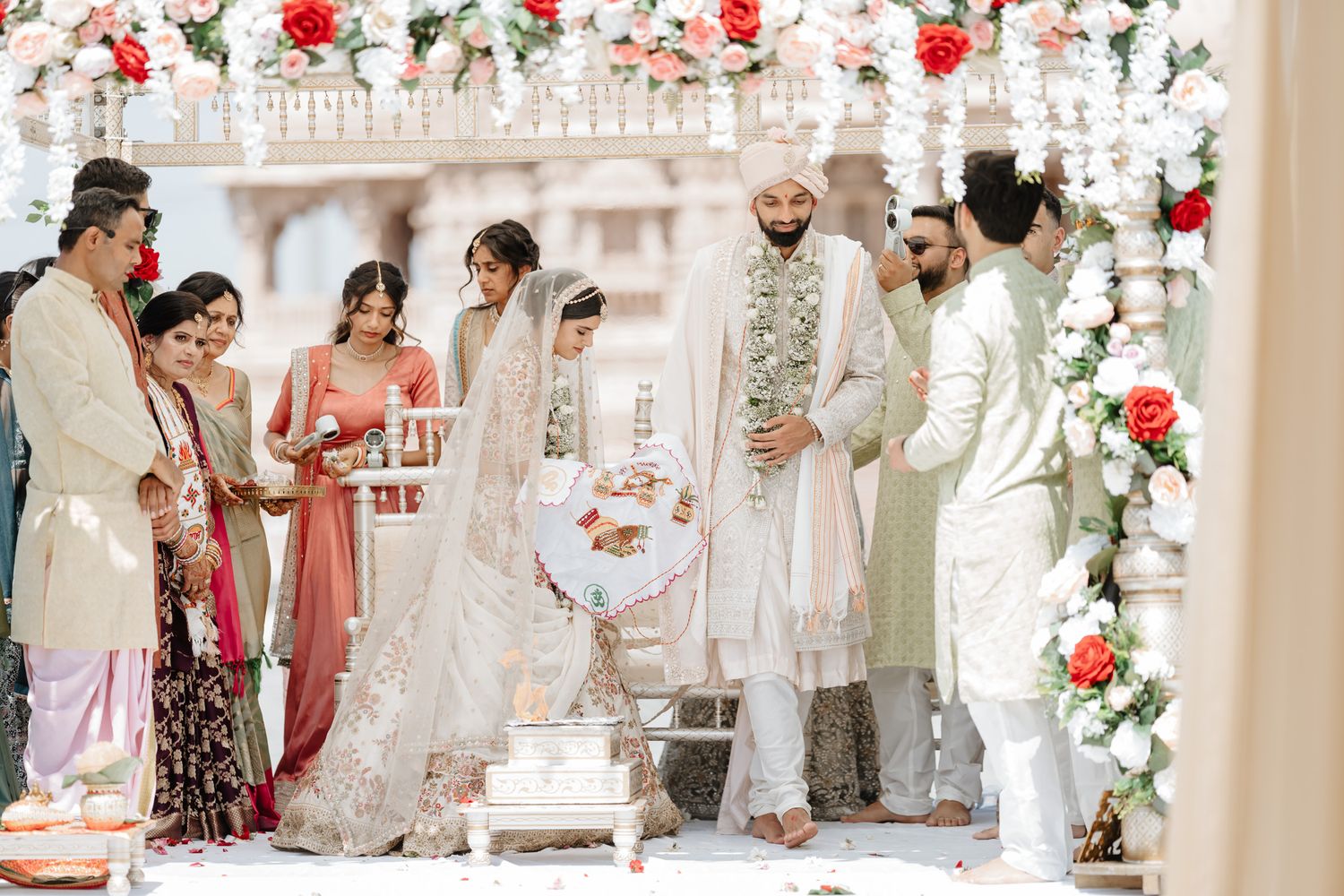 Traditional Indian wedding ceremony with floral decorations and guests gathered under an archway.