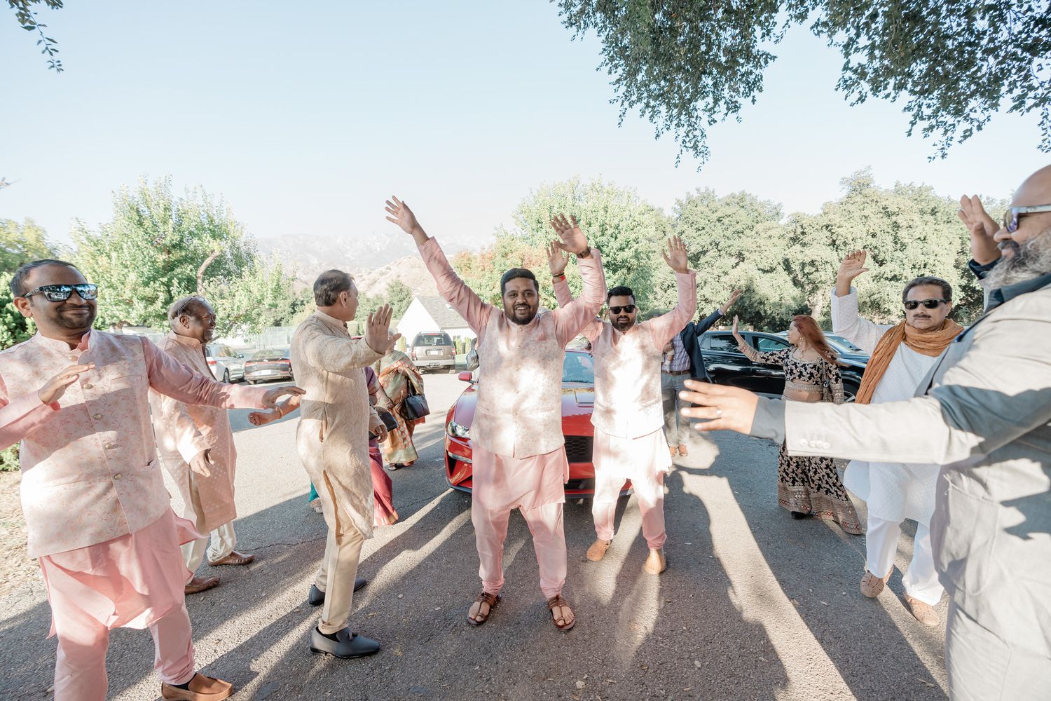 A joyful group celebrates outdoors in colorful traditional Indian attire during a festive gathering.