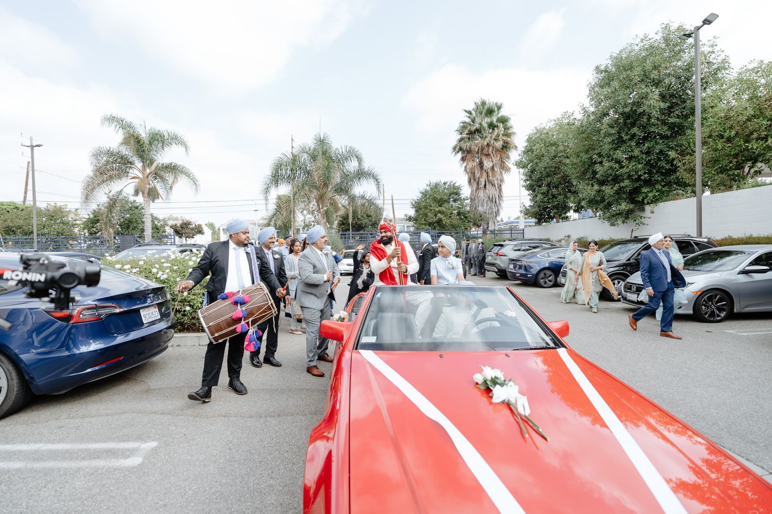 Red and blue luxury cars parked in a lot during a wedding celebration.