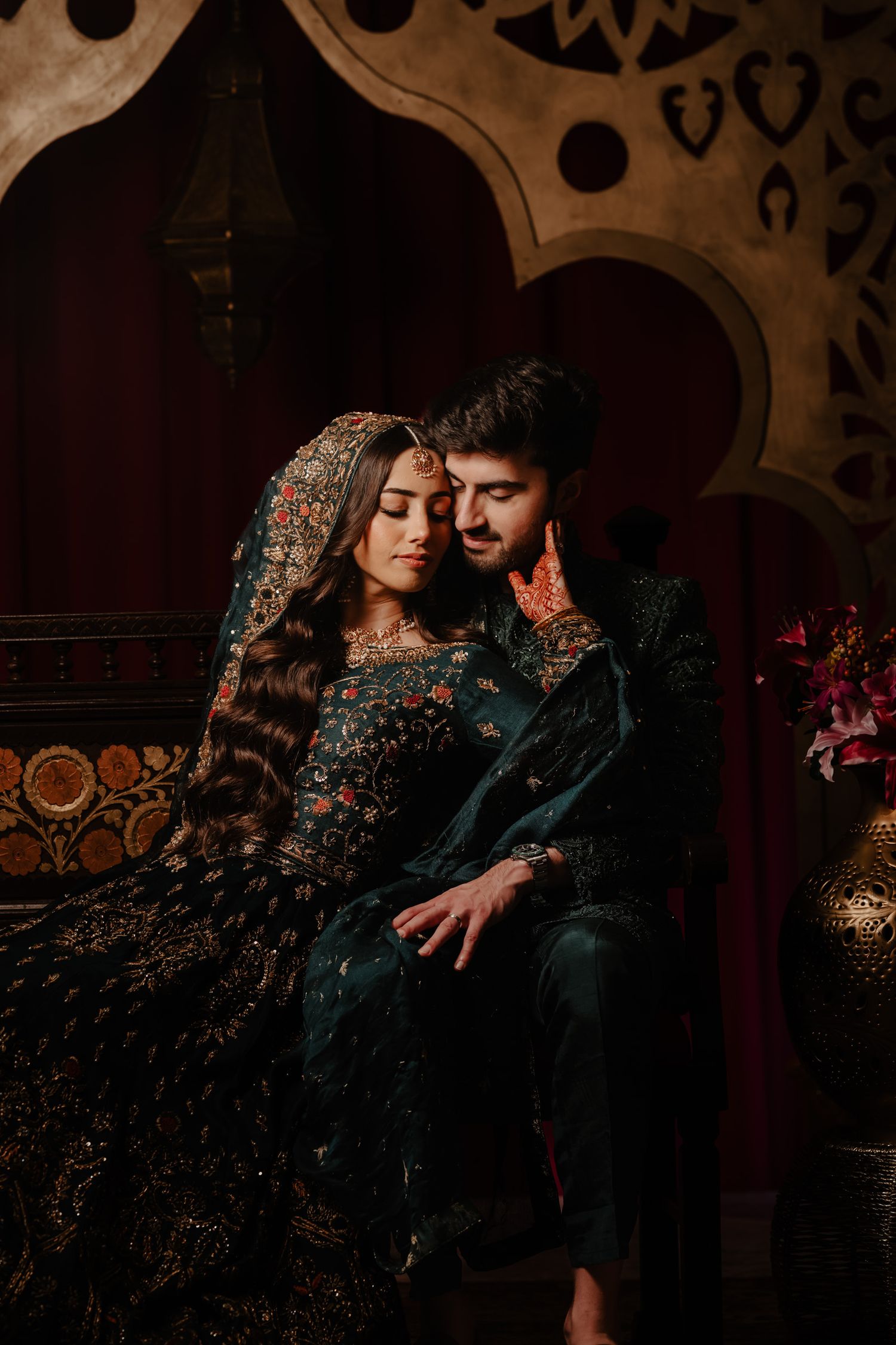 A romantic couple embraces in dramatic dark lighting wearing traditional South Asian attire.