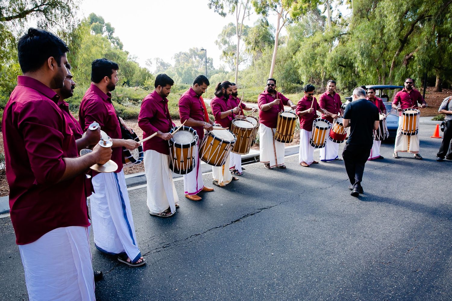 Drummers in burgundy uniforms perform together during an outdoor musical event.