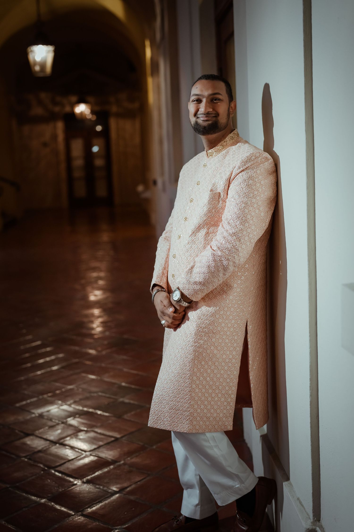 Elegant white embroidered kurta fashion photography against dark stone floor and light colored walls.