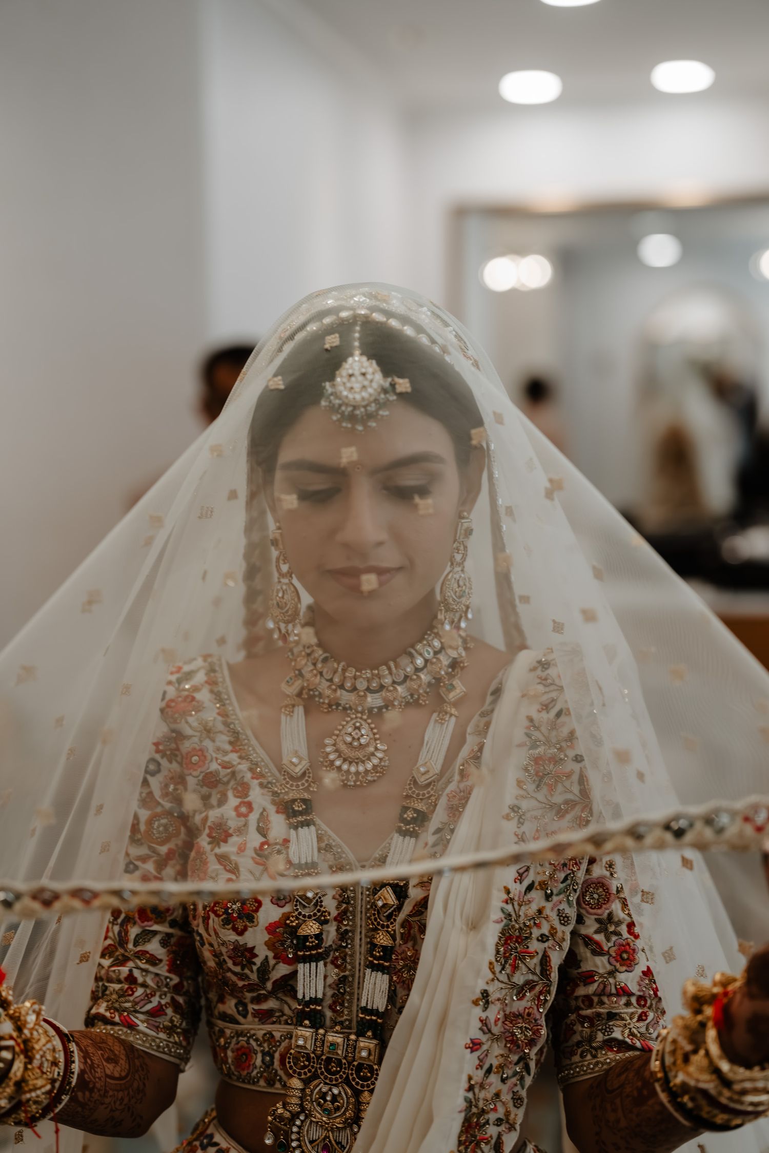 Close-up shots of a bride in traditional Indian wedding attire wearing intricate jewelry and veil details.