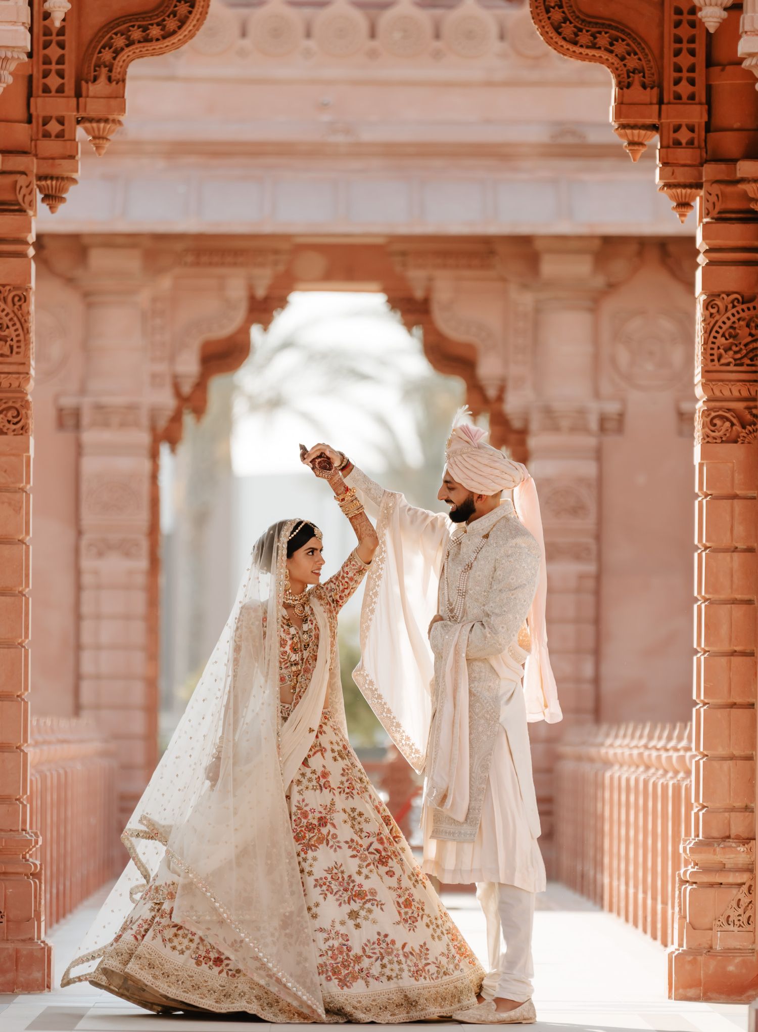 Traditional Indian wedding attire displayed in ornate architectural setting with arched columns.