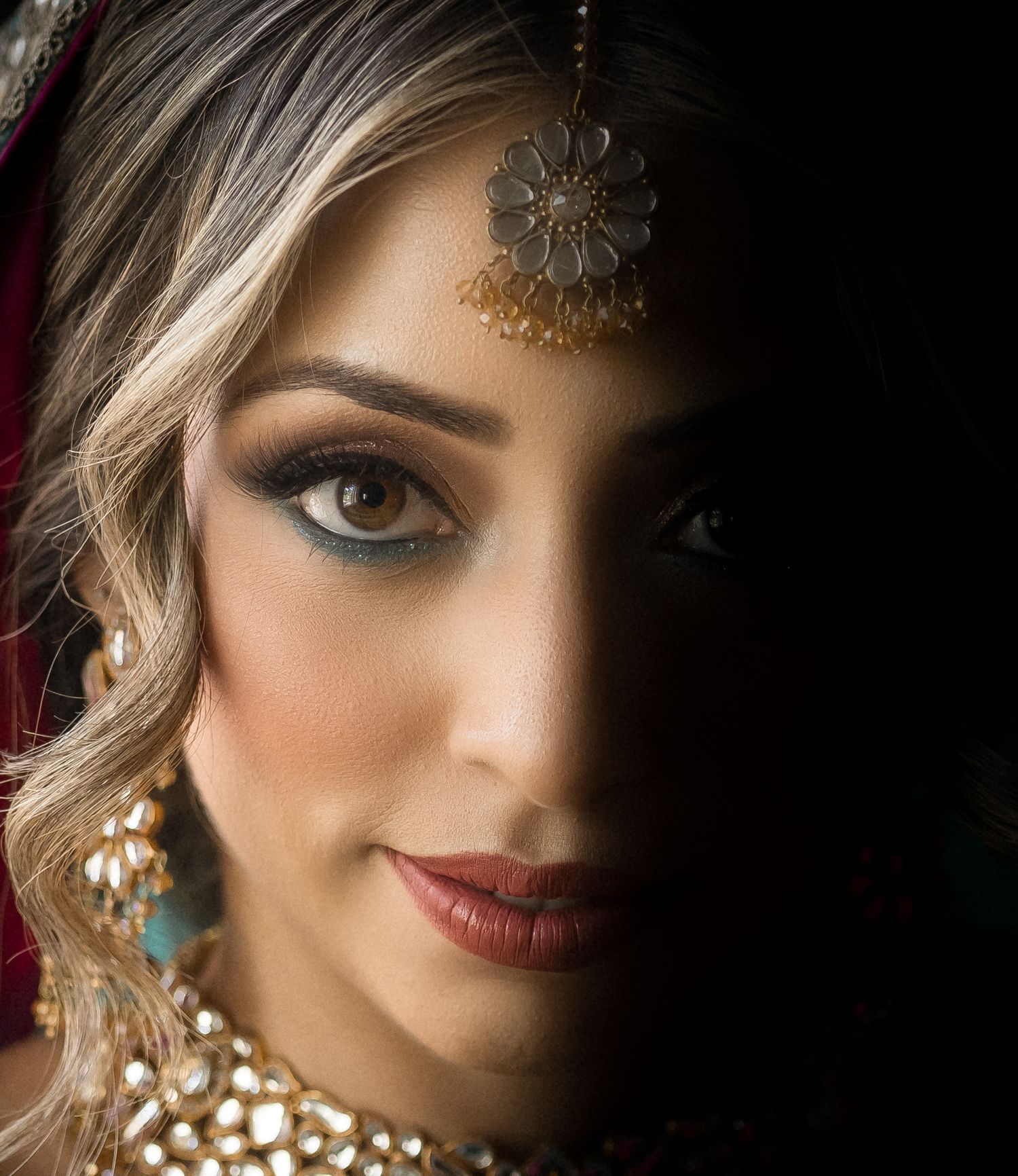 Close up portrait with dramatic lighting showcasing elegant makeup and jewelry details.