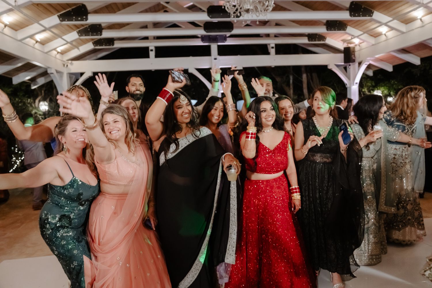 Wedding guests dancing and celebrating on a dance floor at an evening reception party.