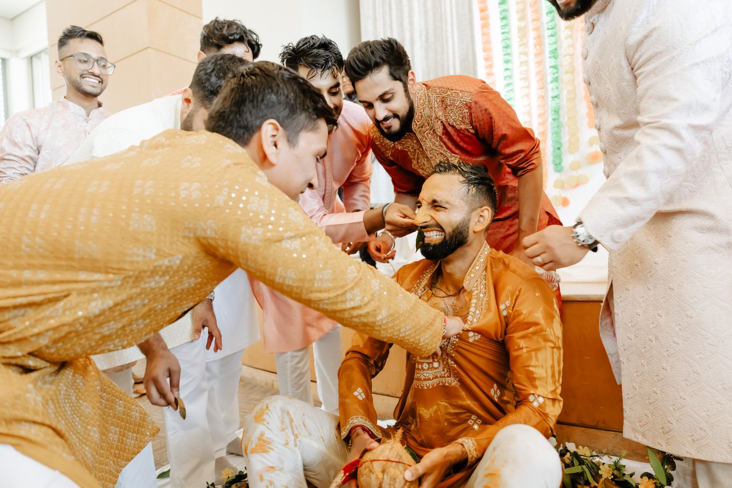 Joyful celebration during an Indian wedding ceremony with guests in traditional orange and white attire.