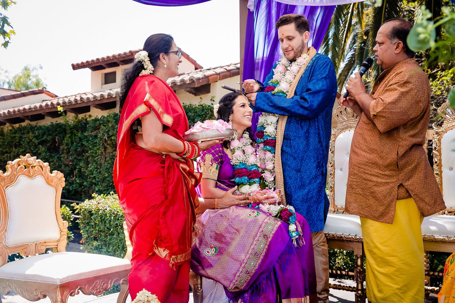A group of people in vibrant traditional Indian attire celebrate during a festive event in an outdoor setting.