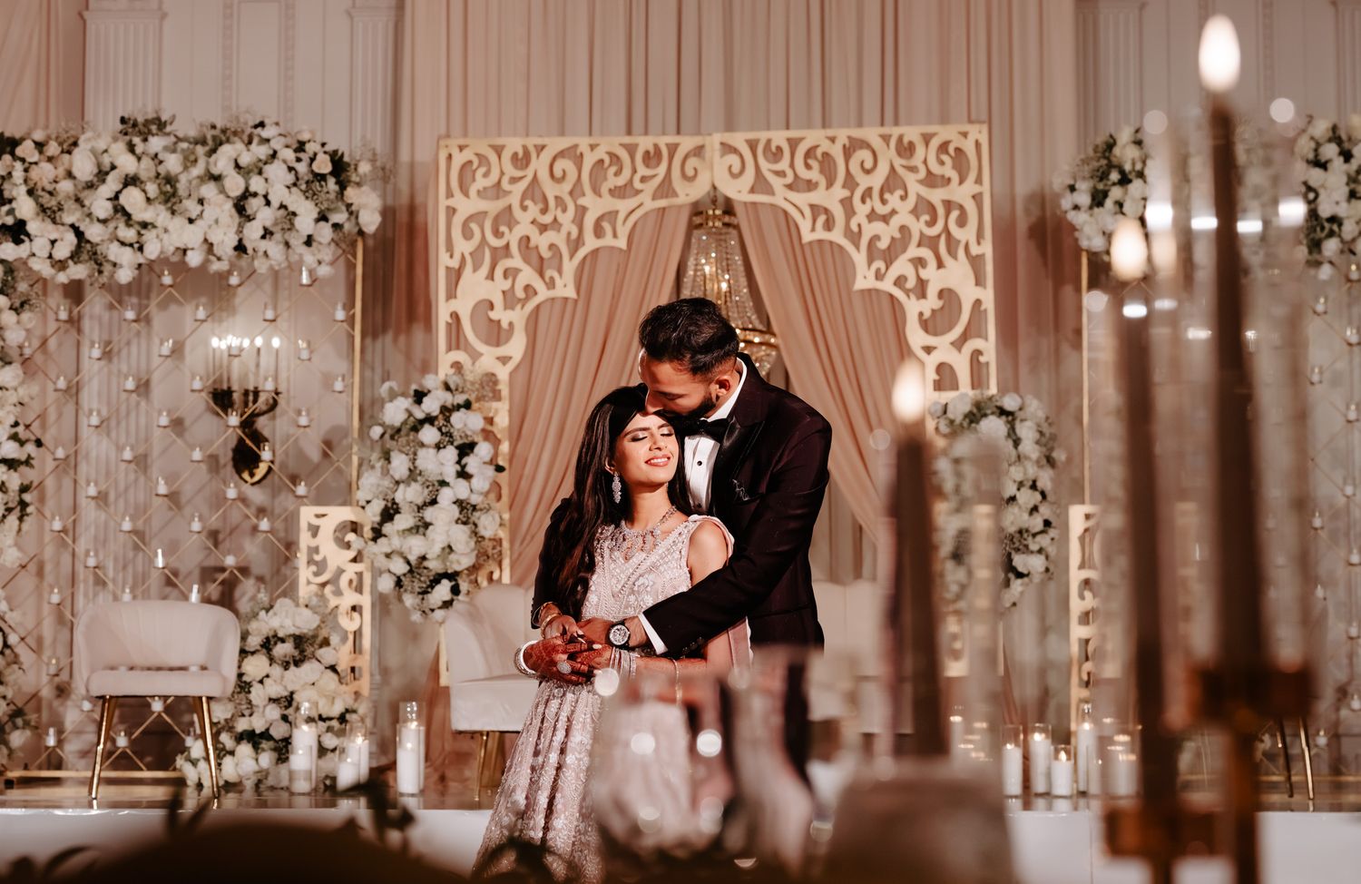 A romantic wedding reception venue decorated with elegant lighting, floral arrangements, and ornate details throughout the space.