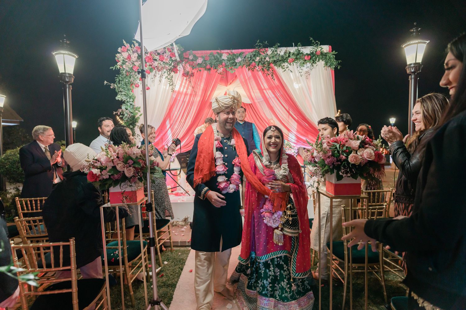 A wedding reception dance floor with guests dancing under romantic lighting and pink decor.