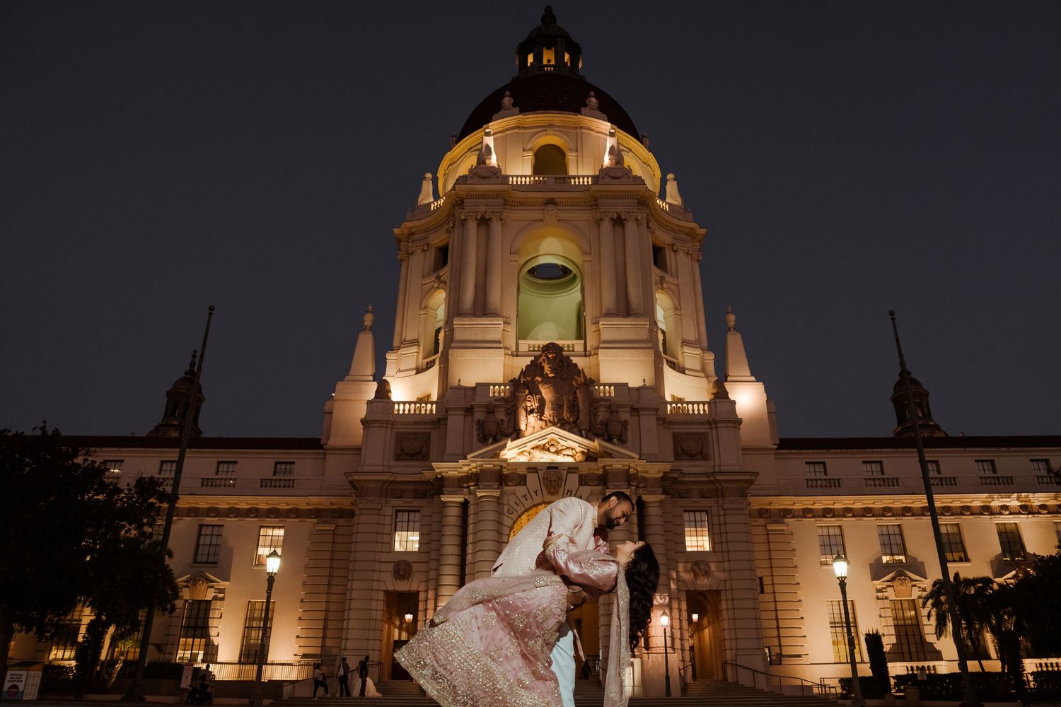Illuminated government buildings at night creating a dramatic architectural backdrop for a wedding photo.
