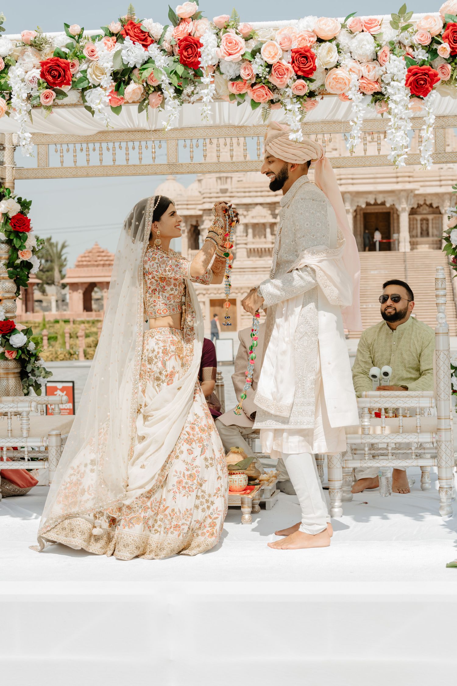 Traditional Indian wedding ceremony setup with red and pink floral arrangements and white decor elements.