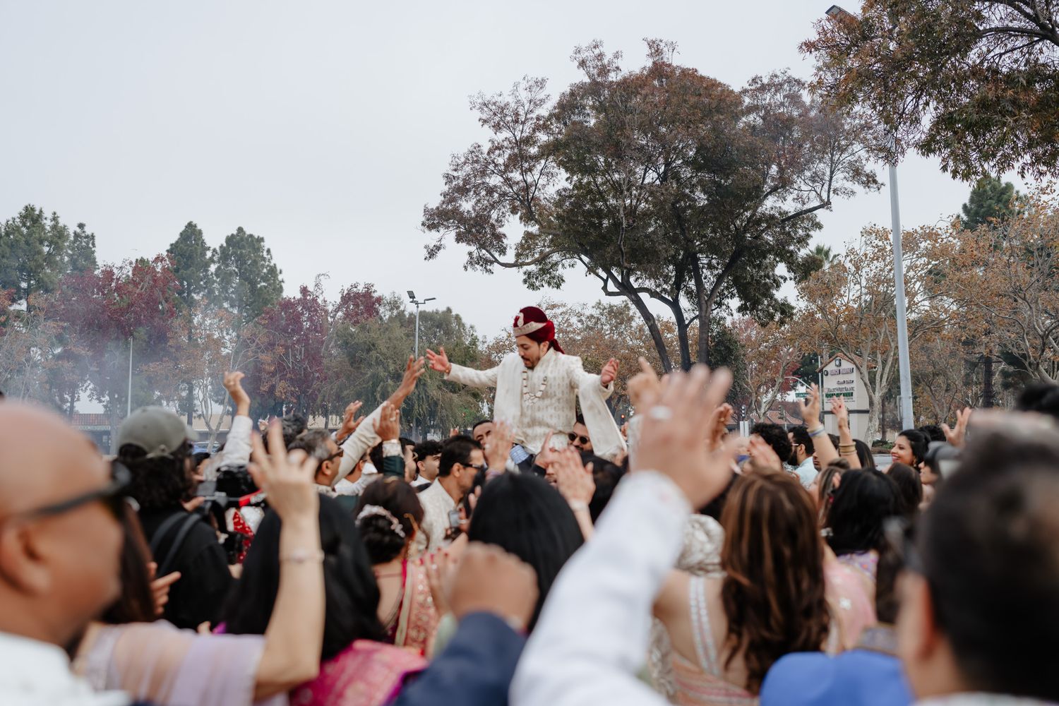 Crowd of people holding up their phones to capture a moment at an outdoor event during daytime.