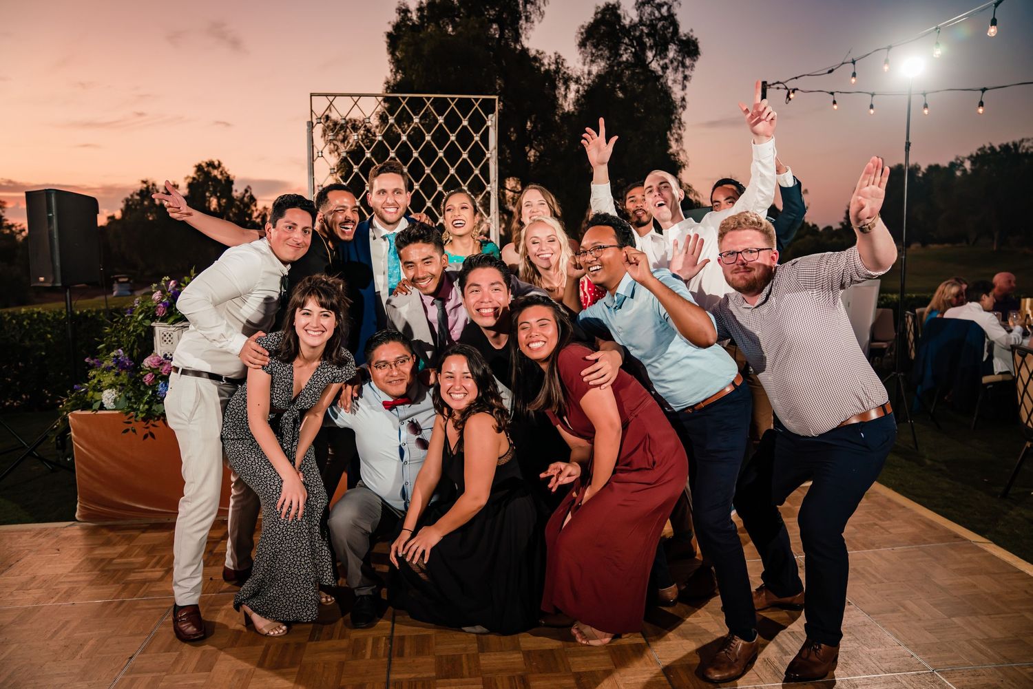 Guests dancing and celebrating at an outdoor evening wedding reception with string lights overhead.