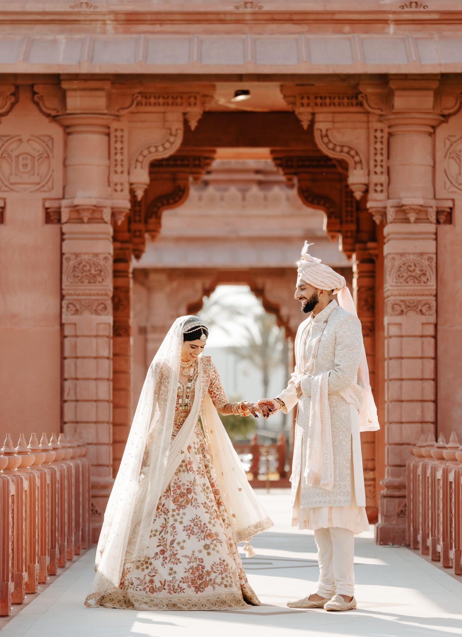 Traditional wedding ceremony in an ornate architectural corridor with decorative pillars and arches.