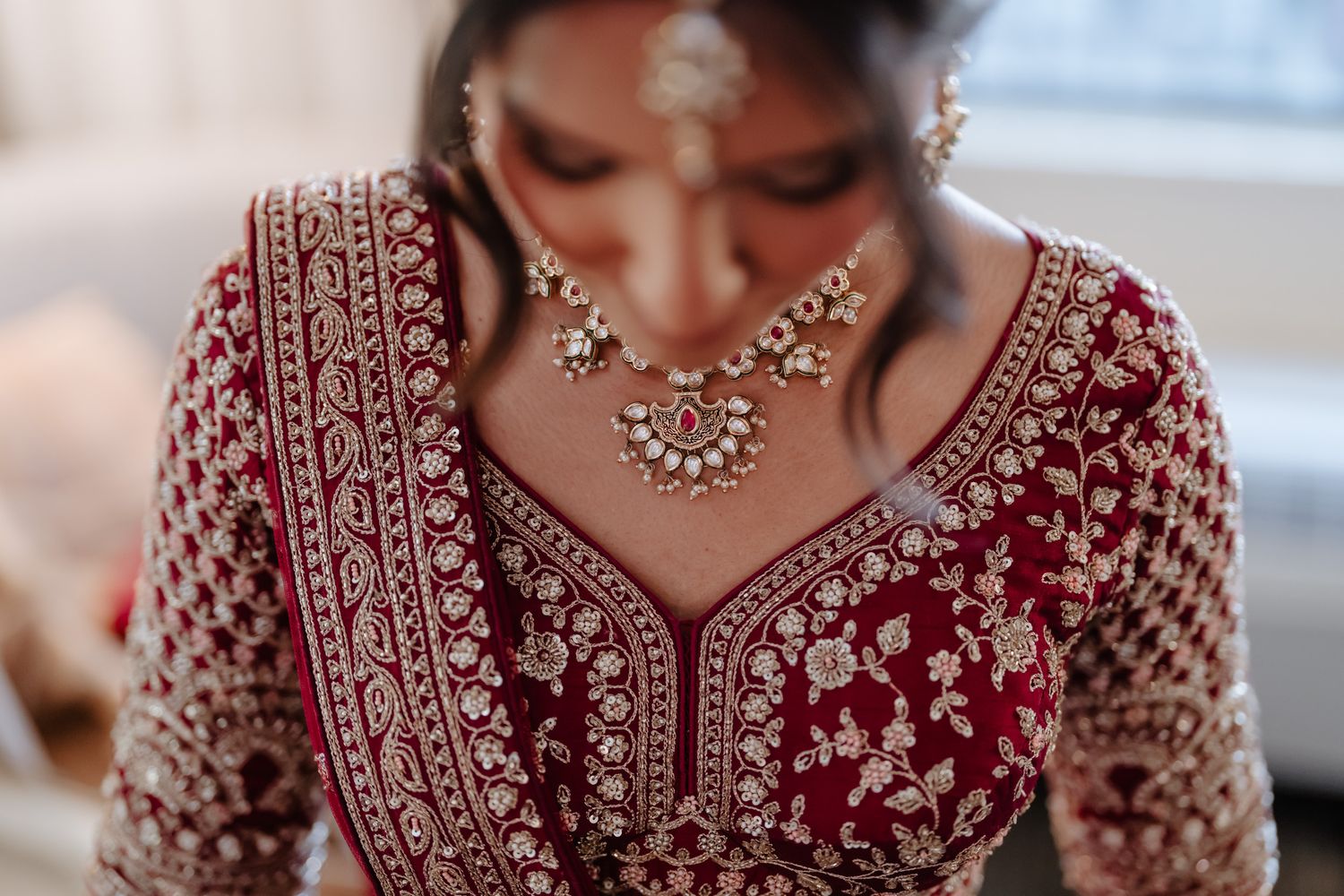 Close-up details of intricate red and gold embroidery on traditional Indian bridal attire.