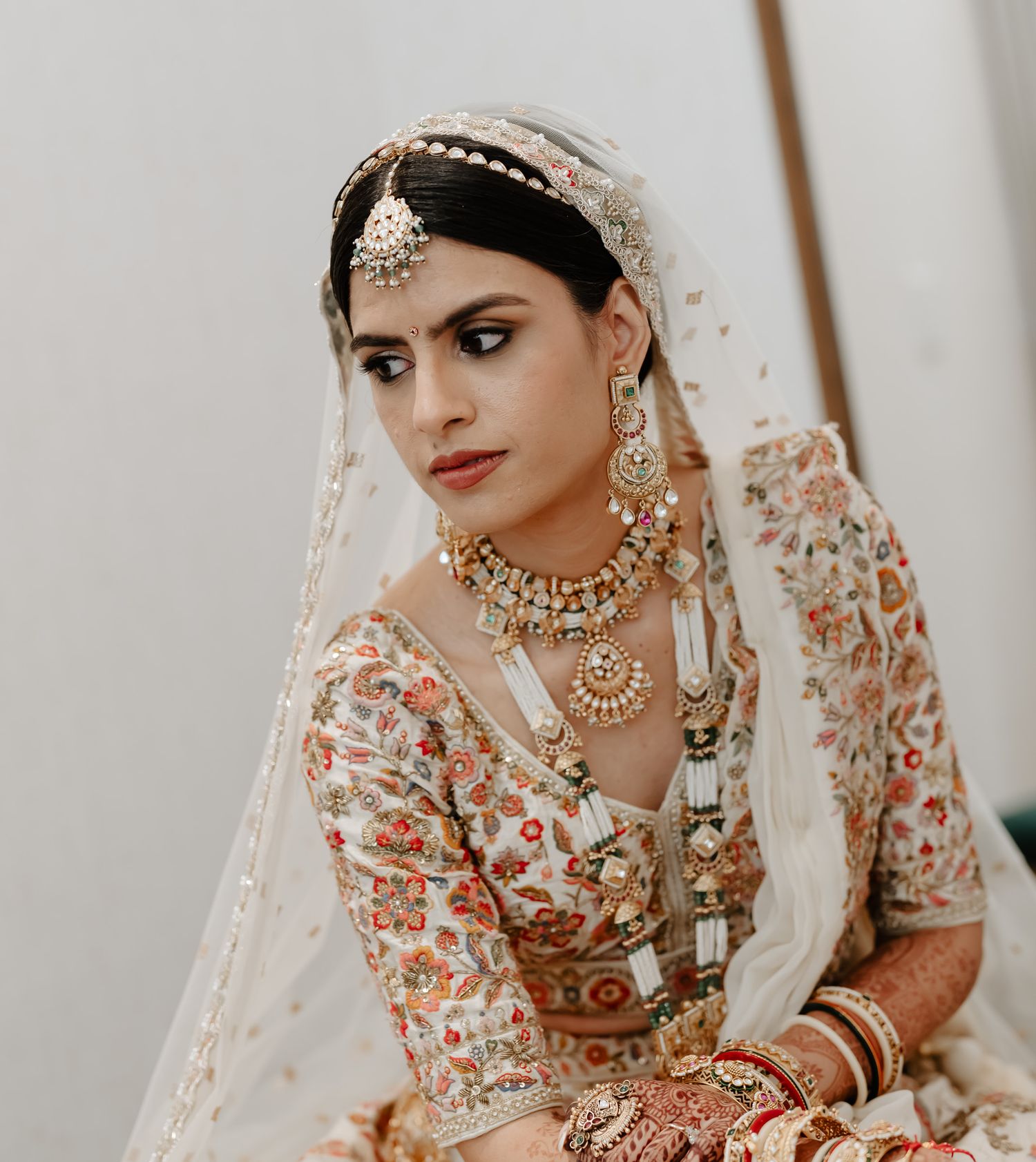 Traditional Indian bridal jewelry and attire with detailed embroidery and ornate accessories.