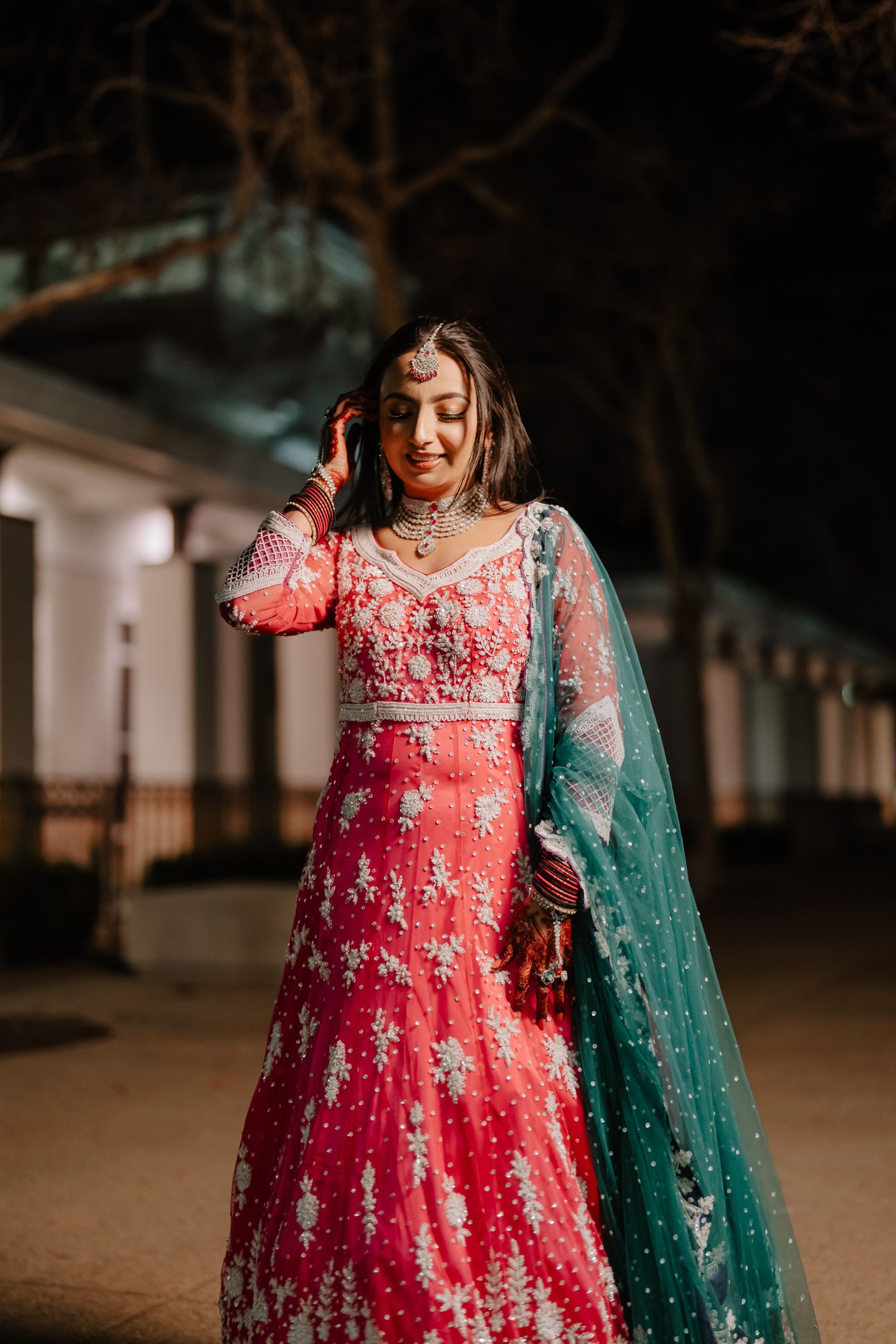 Traditional Indian wedding attire featuring a red embroidered dress with green dupatta captured in evening light.