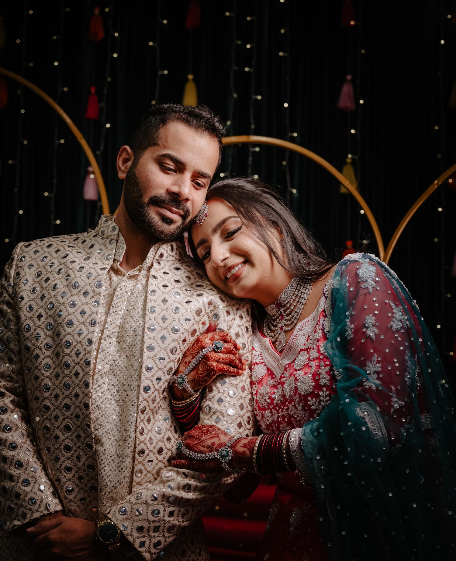 A couple in traditional Indian attire share intimate moments against a dark background with twinkling lights.