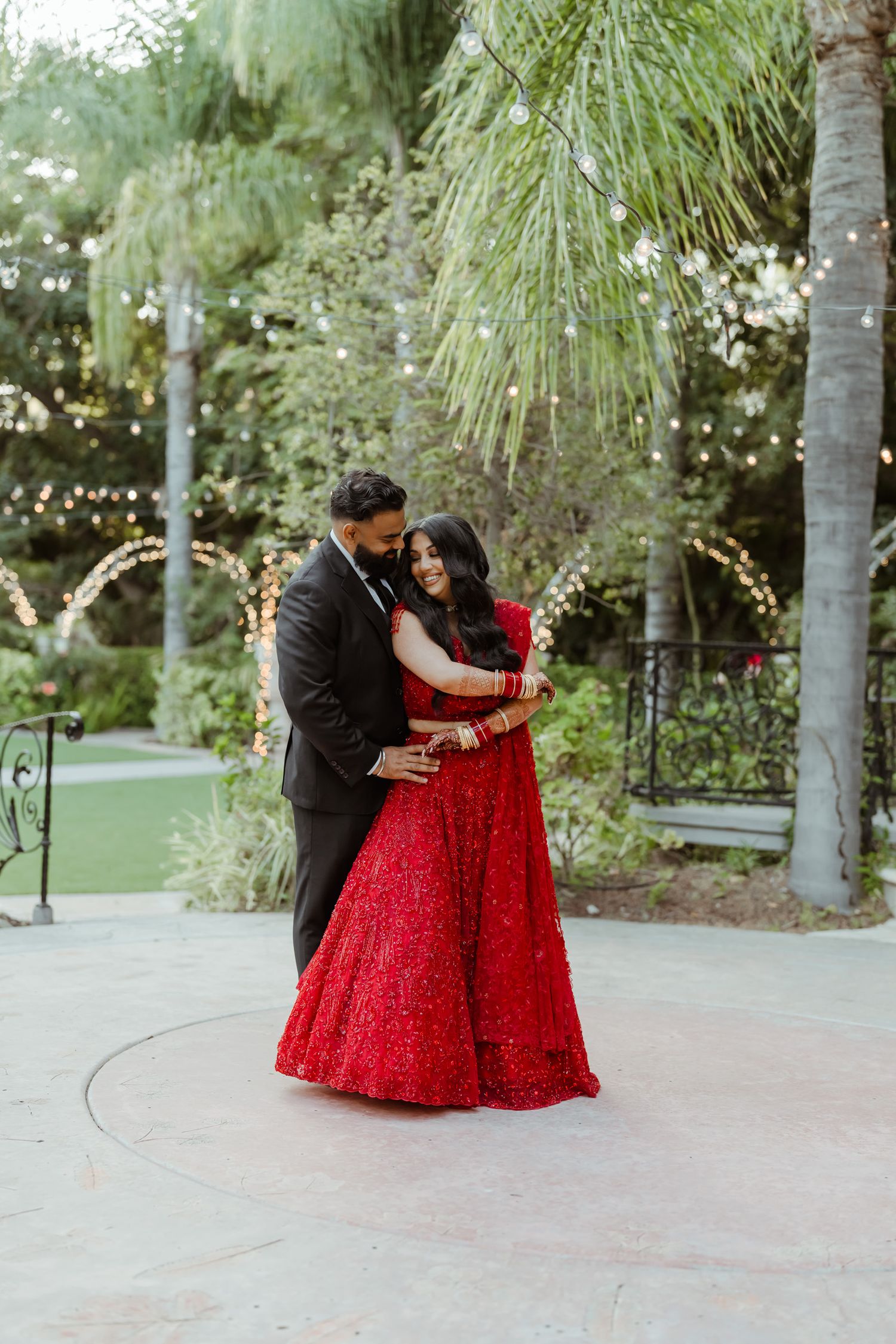 Romantic outdoor photoshoot under palm trees with couple in traditional Indian wedding attire.